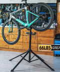 Beast Bike Repair Stand Up To 66 Lbs Aluminum Alloy Portable Home Shop Maintenance Stand lifting a bike in a garage.