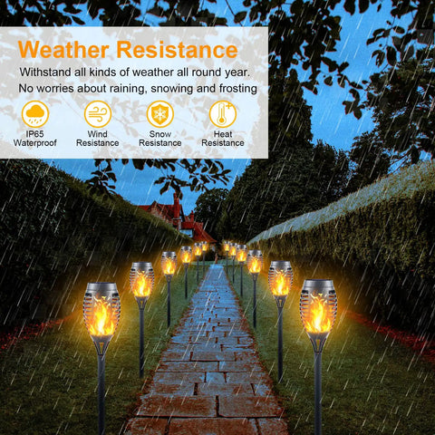 Outdoor garden path lined with 12 Pack Solar Torch Lights Outdoor Flickering Flame Tiki Torches With Auto On Off Upgraded 12 LED Mini Solar Powered Pathway Lights IP65 Waterproof Fire Effect Decor For Garden Patio And Pathway under rain.