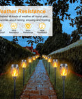 Mini Solar Torch Lights With Flickering Flame Upgraded 12 LED Outdoor Waterproof Tiki Torches illuminating a rainy pathway