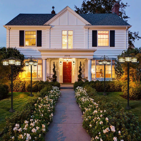76 Inch Black Solar Lamp Post Light With Three Heads illuminating driveway of white house with garden