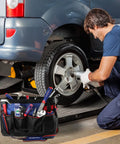 Mechanic using tools from 18 Inch Open Top Tool Bag With Waterproof Molded Base, 20 Pockets, And Adjustable Shoulder Strap in garage