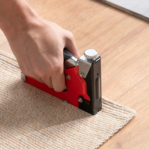 Hand using Beast Of A 4 In 1 Heavy Duty Upholstery Staple Gun Kit on carpet edge for woodworking and DIY furniture projects