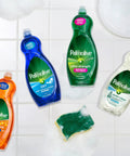Four Palmolive dish soap bottles, including Oxy Power Degreaser, on a tiled surface with a sponge and white soap bubbles.