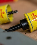 Close-up of Cordless HSS Bi Metal Hole Saw 27mm CSC27 on a workshop table, showing the teeth and alloy body in yellow.