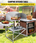 Aluminum Portable Folding Camp Kitchen Table With Windscreen Cupboard And Storage Organizer Carrying Bag For Outdoor Picnics Beach BBQ RV Travel Quick Setup Brown Finish in a picnic setting.