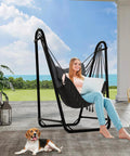 Woman relaxing on U Shaped Hammock Chair With Stand For Indoor Or Outdoor Relaxation Sturdy Rust Resistant Cozy Gray Cotton Swing Chair No Overhead Beam Design For Wider View Porch Patio Balcony Chill And Unwind In Style