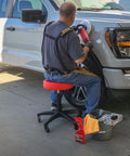 Rolling Shop Stool With Adjustable Height For Mechanics Padded Garage Seat With Smooth Rolling Wheels And ABEC Bearings Model 240250 Red in use by a mechanic working on a truck.