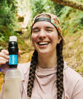 Woman holding Portable Squeeze Water Filtration System with Two 32 Oz Pouches, Straw, and Hydration Pack Adapter in nature