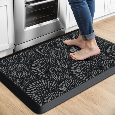 Ergonomic 0.47-Inch Thick Kitchen Mat With Non Slip Waterproof Standing Pad For Home Or Office Comfortable Foam Cushion Large 17.3 By 28 Inch Rug Great For Kitchen Laundry Black showing a person standing on it in a kitchen.