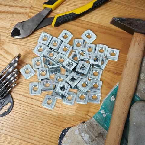 Forty Pack Carbon Steel T Slot Nuts providing a slick sliding fit on wood surface with tools in background.