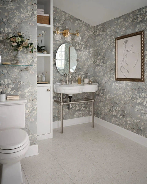 Elegant bathroom with floral wallpaper, round mirror, modern toilet, and partial view of Banbury 22.75 Inch Glass Shelf In Brushed Nickel With Tempered Glass Spot Resist Finish Includes Mounting Template Compatible With Banbury Faucets And Accessories Durable Bathroom Storage on the left.