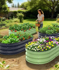 Woman near multiple raised beds with flowers and vegetables in a garden, showcasing colorful planters filled with diverse plants.