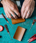 Hands using Badass Professional Grade Three Pack Leather Awl Tools With Grippy Gourd Shaped Wooden Handles for leather crafting.