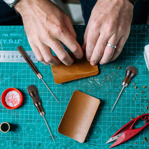Hands using Badass Professional Grade Three Pack Leather Awl Tools With Grippy Gourd Shaped Wooden Handles for leather crafting.