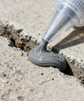 Tough As Nails Concrete Crack Sealant And Fast Cure Waterproof Patch Filler For Driveways And Garages With All Season Grey Caulk being applied to a crack.