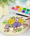 Person painting floral design on plaque from Starter Wood Burning Kit With Burner Pen, 5 Interchangeable Tips, 48-Piece Deluxe Pyrography Set