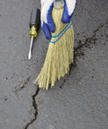 Person preparing asphalt crack for PLI-STIX 60 Ft Asphalt And Concrete Crack Filler 2 Pack For Driveways Self Leveling And Watertight Seal Pro Grade Crack Repair That Works With A Propane Torch Or Heat Gun application with a broom and screwdriver.