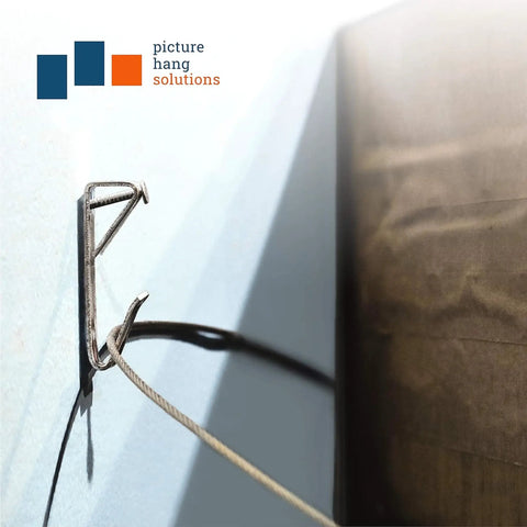 Close-up of a wall-mounted heavy duty picture hangers set 100 lb per hook with nails for hanging photos, canvas art, and mirrors.