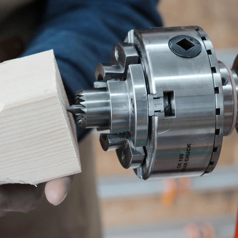Top Tier Crown Drive Center With Spring Loaded Point fits most four jaw chucks, shown with wood piece being held securely.