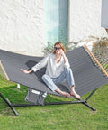 Two Person Outdoor Hammock With Heavy Duty Steel Stand 55 Inch Double Hammock Large Removable Pillow Storage Pockets Easy Setup 475 Lbs Capacity For A Chill Backyard Hangout Haze Gray, featuring woman lounging.