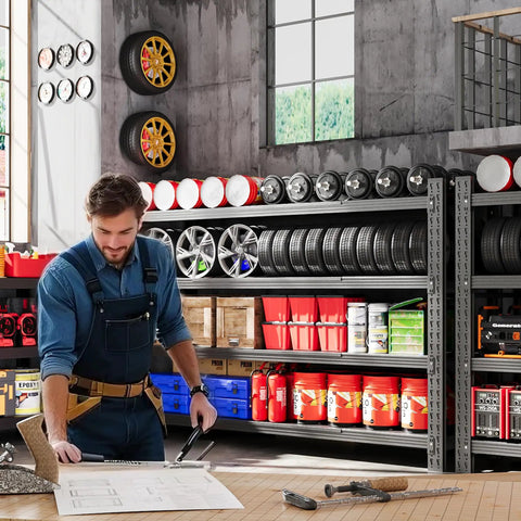 Mechanic working in garage beside heavy duty 4 tier garage shelving unit, 71 inch wide steel storage rack with tires and tools.