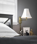 Polished Brass Wall Swing Arm Lamp With Off White Fabric Shade Delivers Classic Vibe And Traditional Style beside bedroom headboard