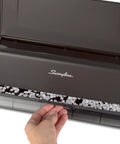Hand accessing tray of electric three hole punch for 28 sheet capacity with auto jam reverse and touch screen control platinum finish