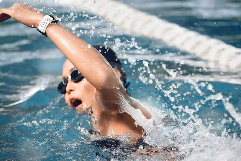 Charge 3 SE Fitness Tracker With Graphite White Silicone Band worn by swimmer in pool, demonstrating water resistance.