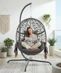 Oversized Hanging Egg Chair With Stand For Indoor Or Outdoor Use, Wicker Bird Cage Swing Chair With Dark Grey Cushion, shown on a patio.