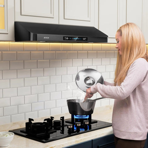 Woman cooking under 36 Inch Under Cabinet Range Hood With 900 CFM Dual Motors Black Kitchen Vent Hood For Real Heavy Duty Cooking