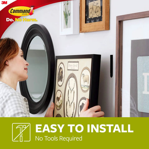 Person using Picture Hanging Strips Medium Black 24 Pairs Pack Holds Up To 12 Lbs Damage Free Decor No Holes No Residue Wall Safe Easy On Your Walls