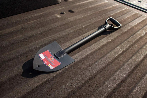 14 Gauge Round Point Trunk Shovel With Poly D Grip Handle resting on ridged surface, showing steel blade and compact design.