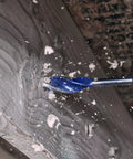 Close-up of IRWIN wood drill bit (blue) in a cordless drill drilling into wood with chips