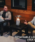 Two men seated by a Mesa XL Heat Deflector With 3 Detachable Legs For Fire Pit Captures And Redirects Warmth In 304 Stainless Steel.