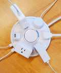 Top view of Six Outlet Surge Protector With USB Charging Station 1080 Joules 6 Ft Cord, plugs inserted on wood surface