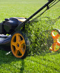 Lawnmower cutting grass in a field with yellow wheels and green clippings being discharged.