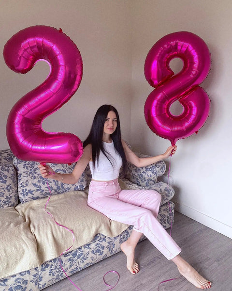Woman holding pink foil number 2 and Hot Pink Number 8 Balloon 40 Inch Giant Foil Balloon For 8th Birthday Party Decor Epic Photo Backdrop Prop Large 8 Balloon For Party Supplies Bold Birthday Decor That Pops And Stays Put on sofa