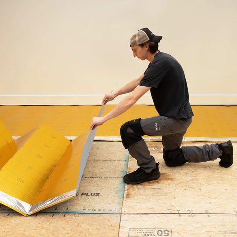 Man installing Premium Flooring Underlayment Roll 100 Sq Ft 2Mm Thick with pre-taped sides on floor.