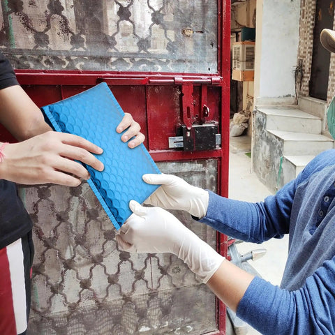 Two people exchanging Blue Aluminum Film Bubble Mailers 50 Count, Built Tough Padded Envelopes With Self Sealing outdoors.