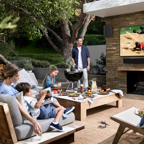 Family enjoying outdoor patio with Bluetooth speakers, showing the 6.5 inch 800W waterproof wired system with wall mount setup.