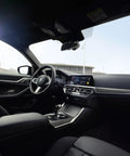 Interior view of a BMW car dashboard with a focus on the steering wheel and console, showcasing design and technology features.