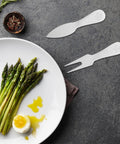 Travel Friendly 5 Piece Cheese Knife Set With Butter Spreader Stainless Steel Utensils on slate next to asparagus dish
