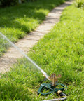 Impact Pulsating Lawn Sprinkler With Metal Base in action, showing water spray on grass, adjustable 360 degree rotation, zinc alloy build