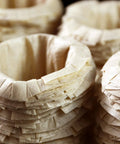 Stacks of unbleached disposable K-Cup paper filters for Keurig, compatible with Ekobrew EZ-Cup, showing texture detail.