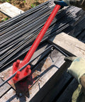 Heavy Duty Manual Rebar Bender For 5/8" Steel Bars in use, bending steel on a job site with gloves on.