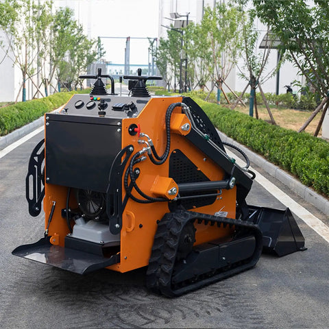 Compact orange tracked mini skid steer loader with backhoe attachment on urban street; hydraulic lifting and control panel visible.