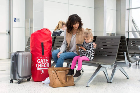 Go To Gate Check Stroller Bag For Umbrella Strollers Travel Bag For Airplane Fits Most Single Umbrella Baby Strollers Airport Essentials For Gate Check Flying Essentials Red next to suitcase at airport