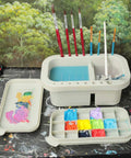 Must-Have Paint Brush Cleaner And Holder With Built-In Palette And Wash Basin For Acrylic, Watercolor, And Water-Based Paints, Compact Portable Organizer In Gray shown in use.