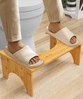 Person using 7 Inch Bamboo Poop Stool For Bathroom For Adults And Kids Relieves Bloating Constipation Eases Defecation Improves Bowel Movements With Anti Slip Grooved Surface Ergonomic Step Stool For Safer Easier Toileting in front of toilet.