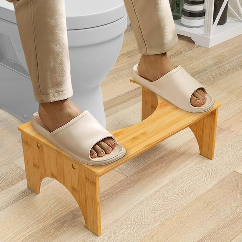 Person using 7 Inch Bamboo Poop Stool For Bathroom For Adults And Kids Relieves Bloating Constipation Eases Defecation Improves Bowel Movements With Anti Slip Grooved Surface Ergonomic Step Stool For Safer Easier Toileting in front of toilet.